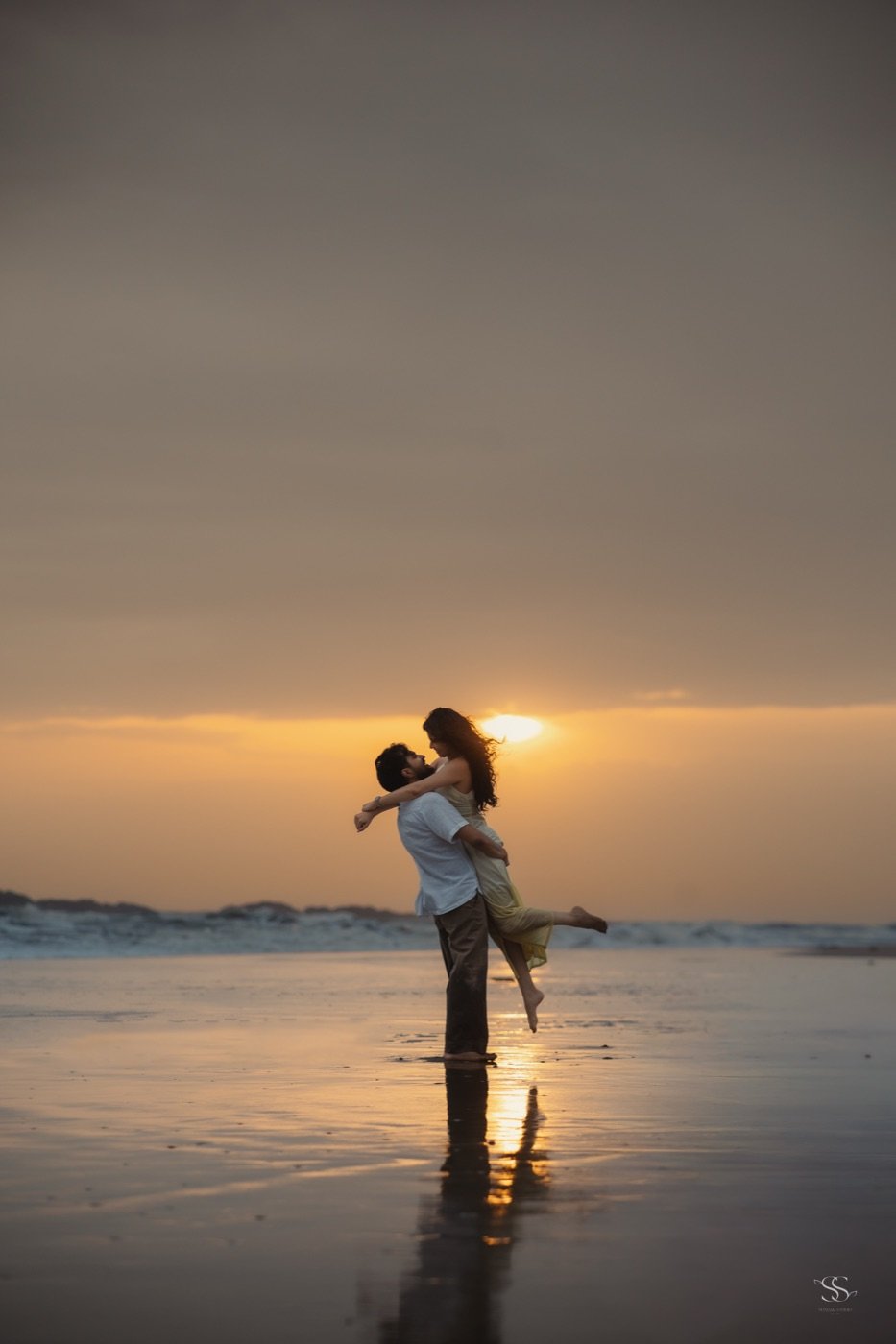 Rohan lifting Ananya on a beach at sunset